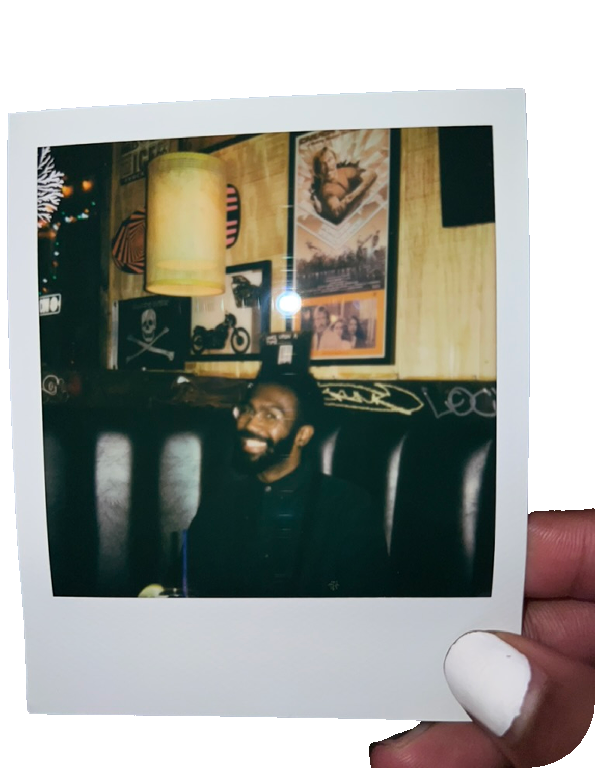 Polaroid photo of Deron smiling in a bar booth